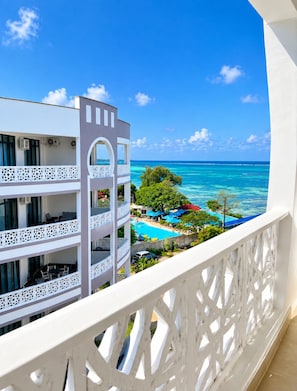 Ein Hotelbalkon mit Blick auf einen Swimmingpool und den Ozean.