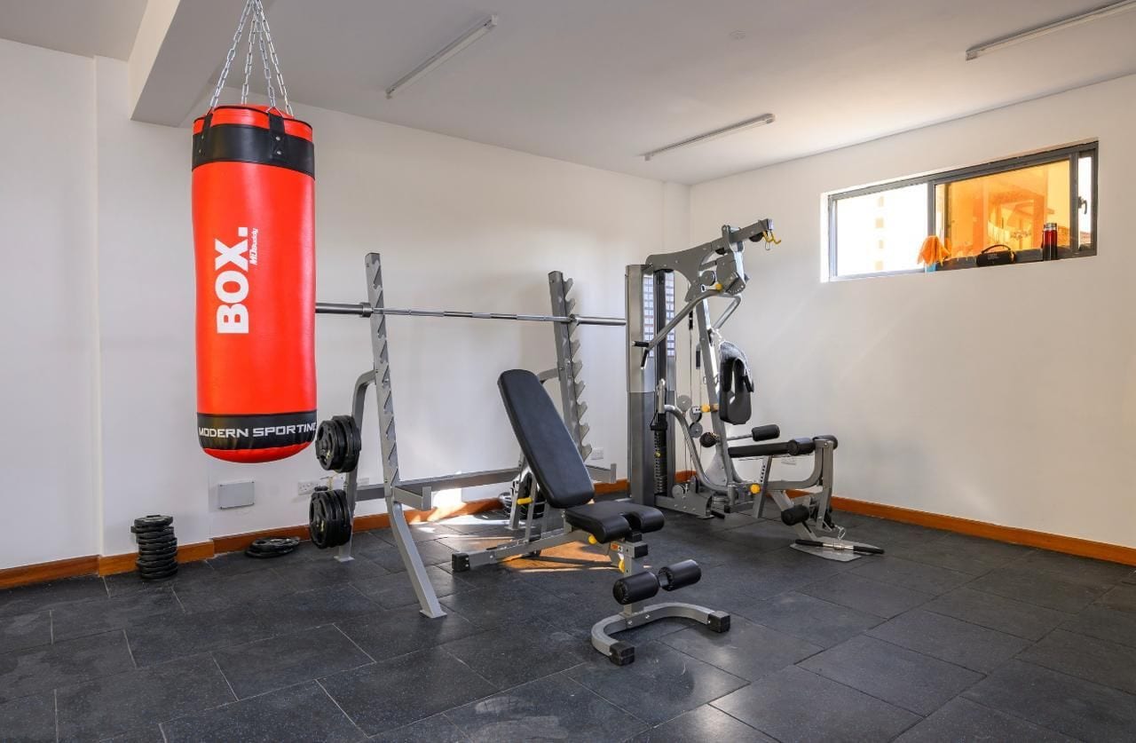 A gym with a punching bag, weight bench, and various exercise machines.