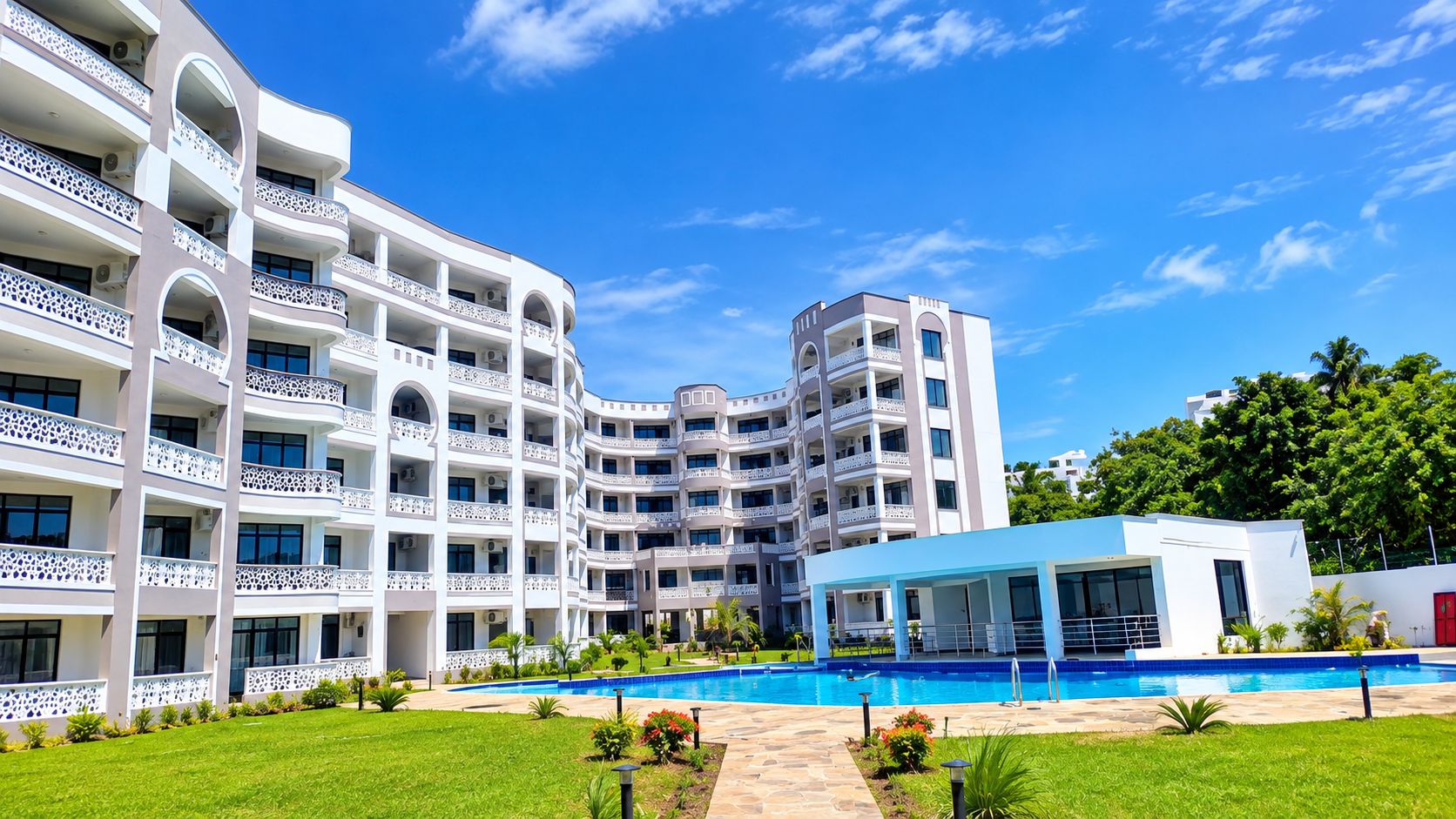 A multi-story hotel with balconies, a swimming pool, and a covered area.