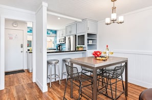 A modern kitchen with a dining area, featuring stainless steel appliances, a wooden table, and black wire mesh chairs. - 25% Off Oct 29-31 Walk 2 Beach/Shops -Pool,Jacuzzi (Ventura)