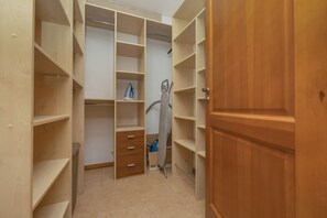 Ein begehbarer Kleiderschrank mit mehreren Regalen und Schubladen, ein Staubsauger und eine Tür.