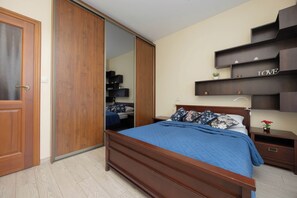A bedroom with a wooden bed, a wardrobe, and built-in shelves with the word 'LOVE' on them. - Warsaw | Biały Kamień 2 | Bright apartment | Free Parking (Warszawa)