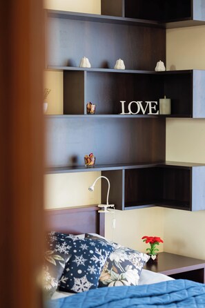 Ein Schlafzimmer mit einem Bett, einem Nachttisch, einer Lampe und einem Regal mit Dekoration und dem Wort 'LOVE'.