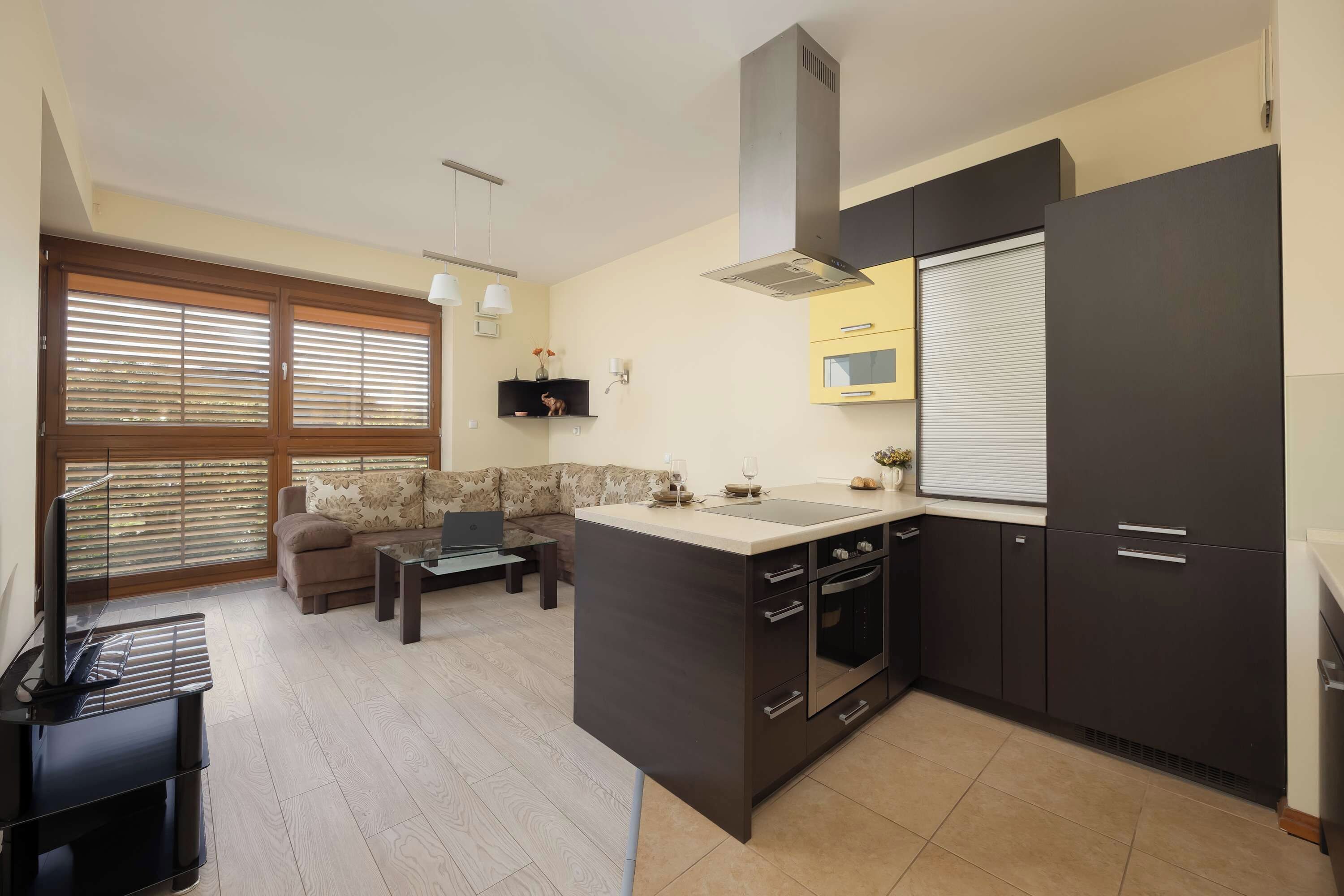 A compact kitchen with dark cabinetry, a central island, and a dining area with a sofa and table.