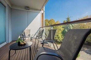 A balcony with a table, chairs, and a potted plant. - Warsaw | Biały Kamień 2 | Bright apartment | Free Parking (Warszawa)