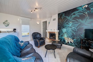 A living room with a fireplace, a large mural, and a sofa. - Cottage 'Gite La Landette' with Private Terrace, Private Garden and Wi-Fi (Lapenty)