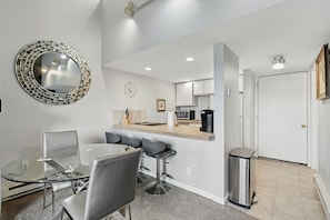 A modern kitchen with a microwave, toaster, and sink. There is a dining area with a glass table and chairs. - Breckenridge Studio Retreat | Great Location (Breckenridge)