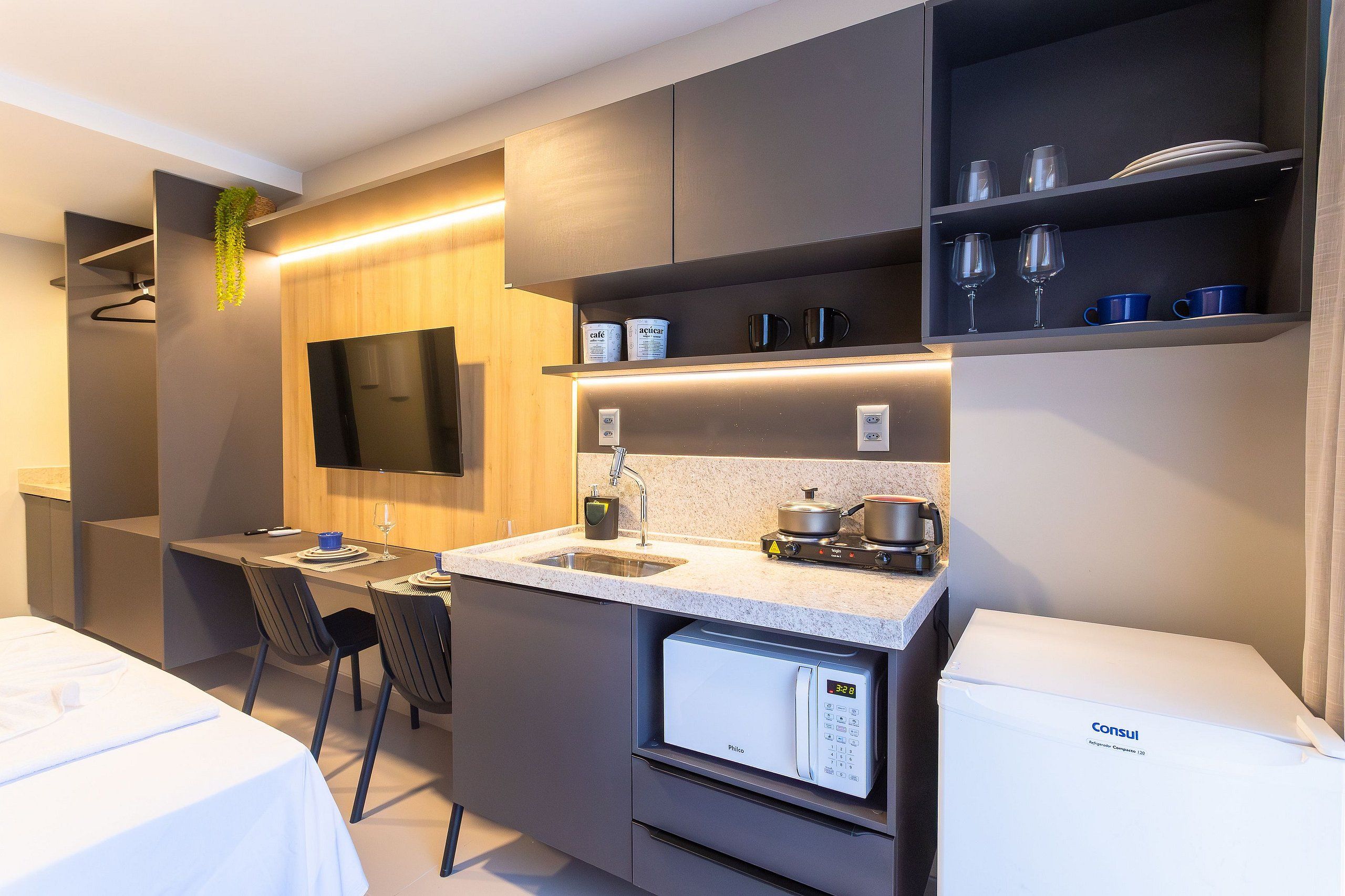Una kitchenette compacta con estufa integrada, un lavamanos y un refrigerador pequeño.