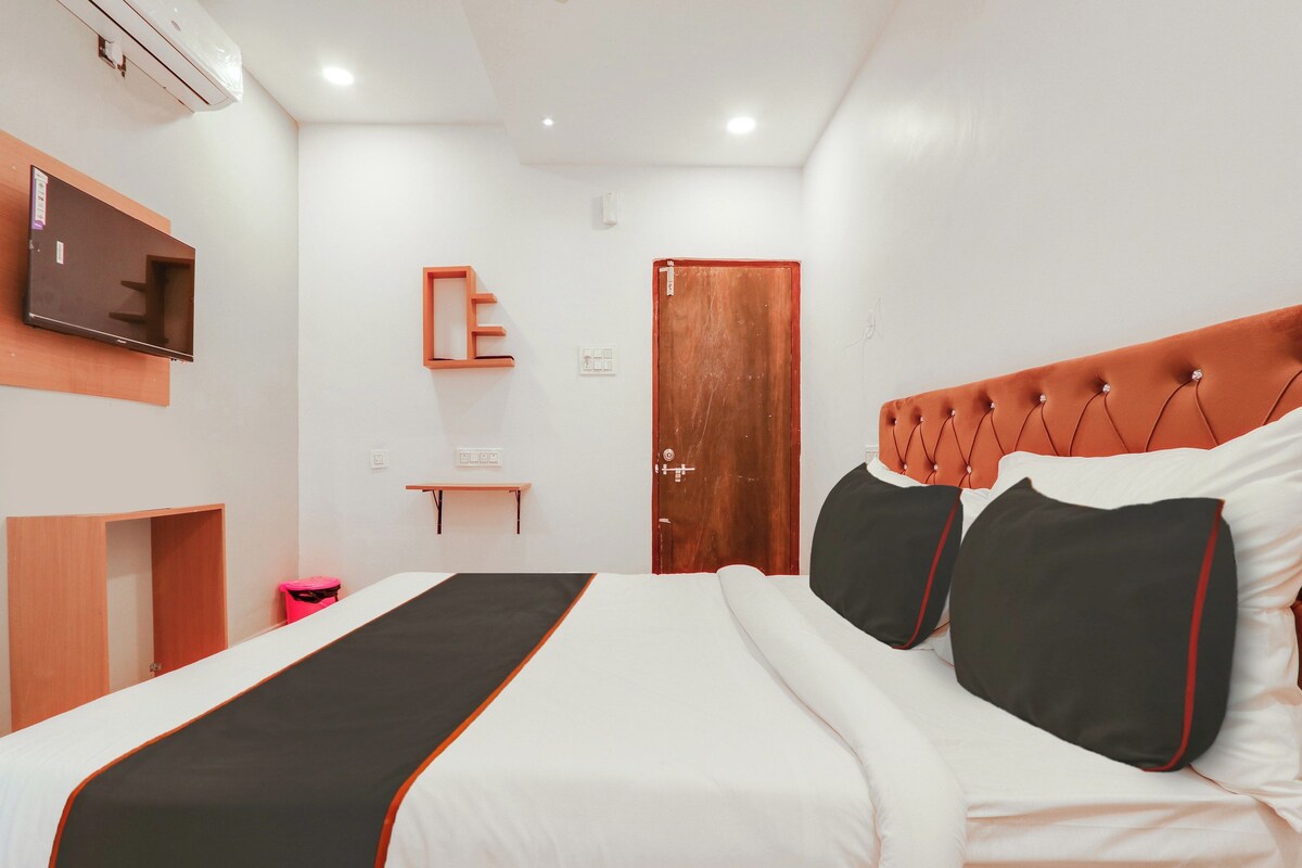 A hotel room with a bed, a television mounted on the wall, a wooden door, and a small table.