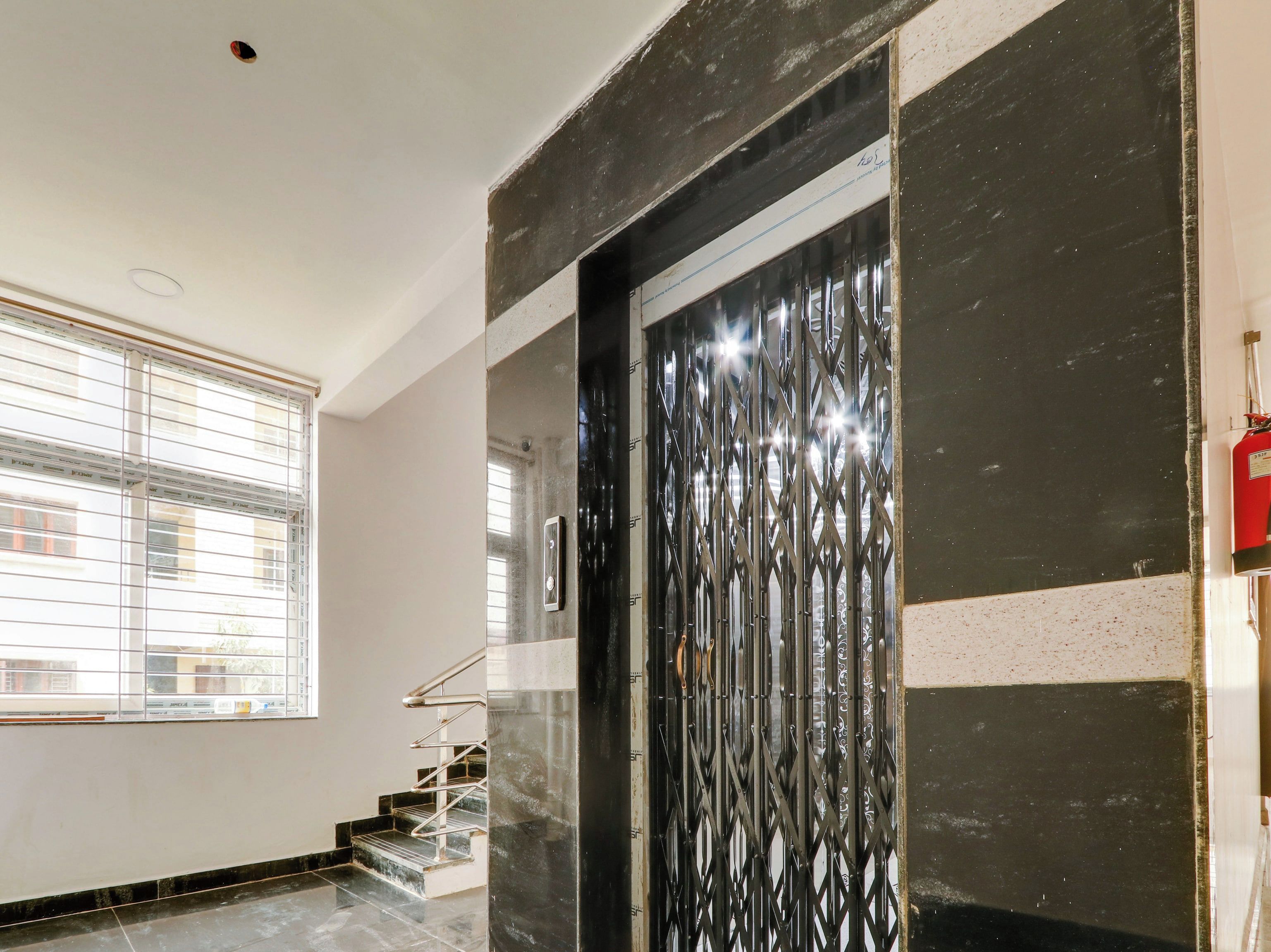 Una escalera con barandillas metálicas que lleva a una puerta con una reja decorativa de metal.