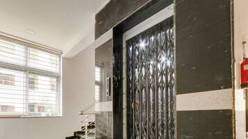 Una escalera con barandillas metálicas que lleva a una puerta con una reja decorativa de metal.