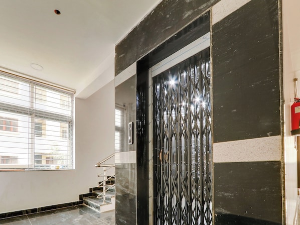 A staircase with metal railings leading to a door with a decorative metal grille. - Collection O White Ridge Kamineni (Hyderabad)