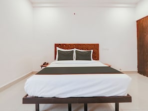 A single bed with a wooden headboard, white bedding, and a telephone on a bedside table. - Collection O White Ridge Kamineni (Hyderabad)