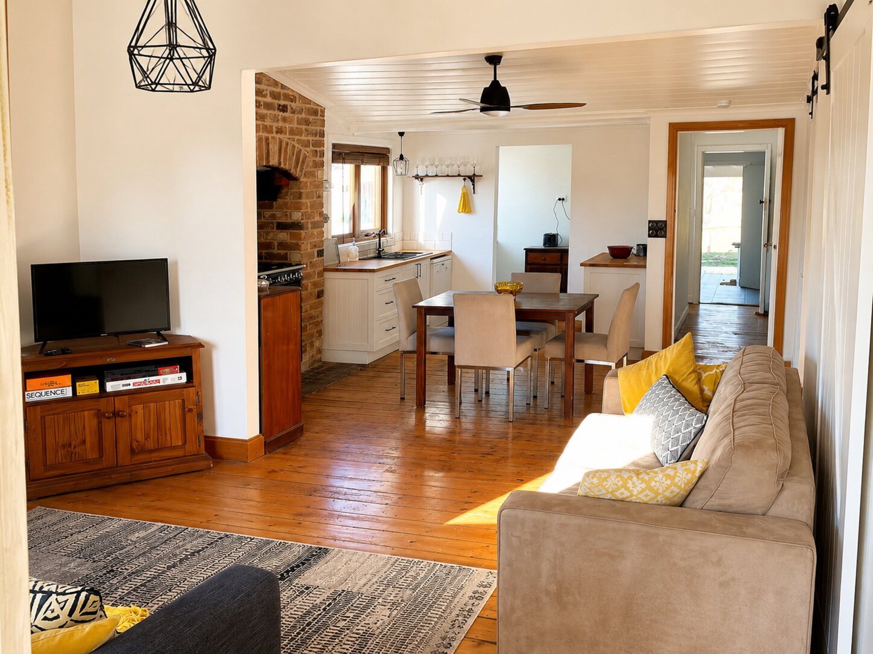 A living room with a sofa, a television, and a kitchen area with a dining table and chairs.