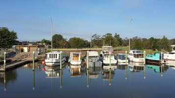 A marina with several boats docked, calm water, and a clear sky.