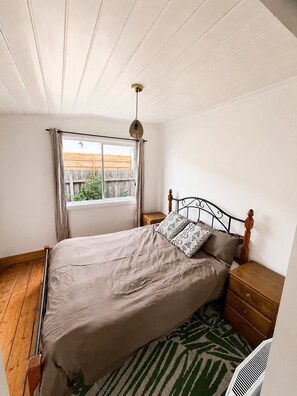 Una camera da letto con un letto, un comodino in legno e una finestra con tende.