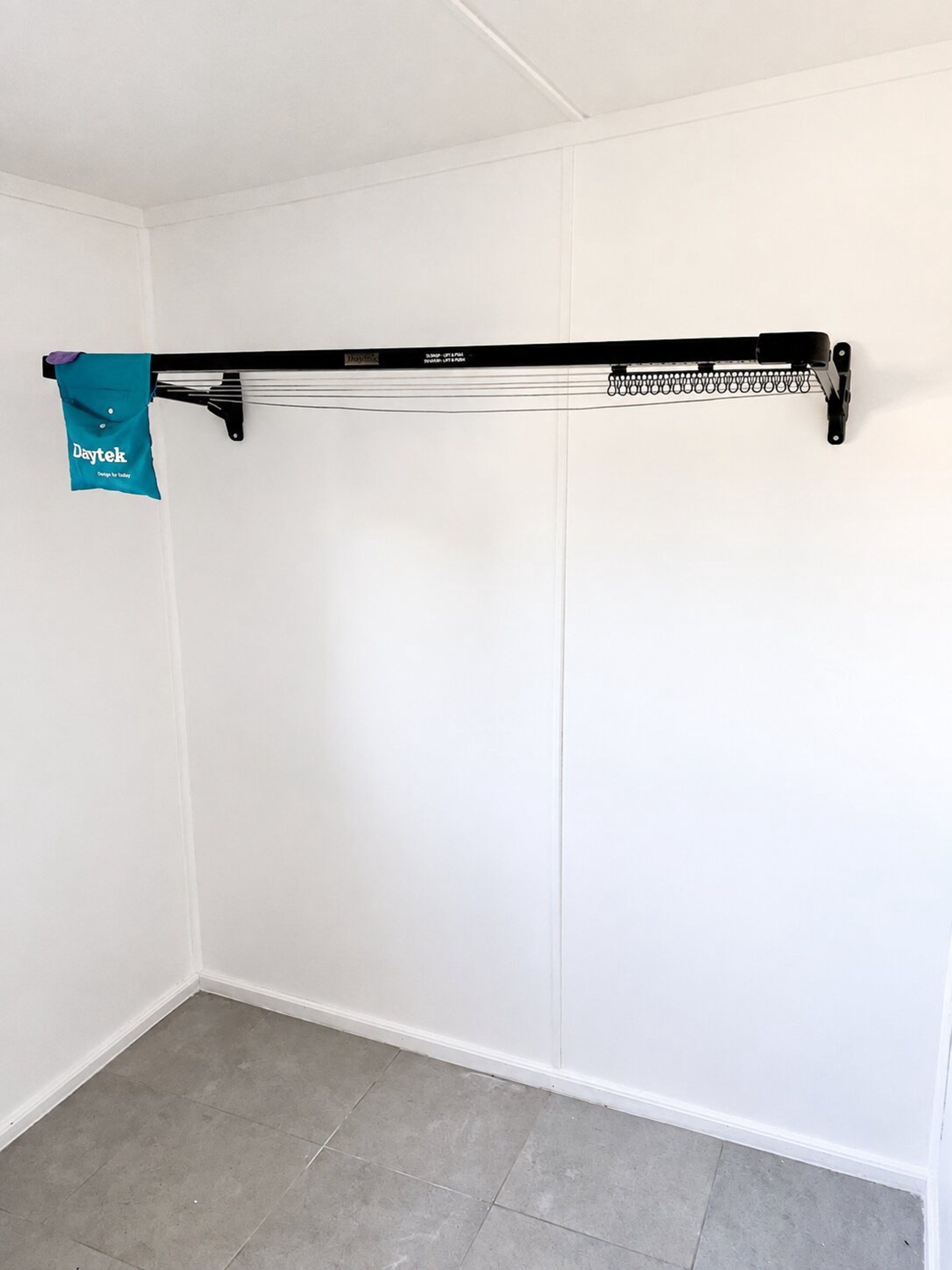 A white closet with a black hanging rod and a blue bag hanging on it.