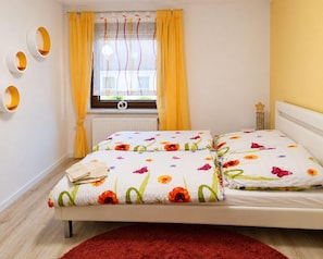 A bedroom with a bed, curtains, a radiator, a window, and a wall-mounted light fixture. - Holiday Home Lieselotte in the Heart of the Thuringian Forest (Brotterode-Trusetal)