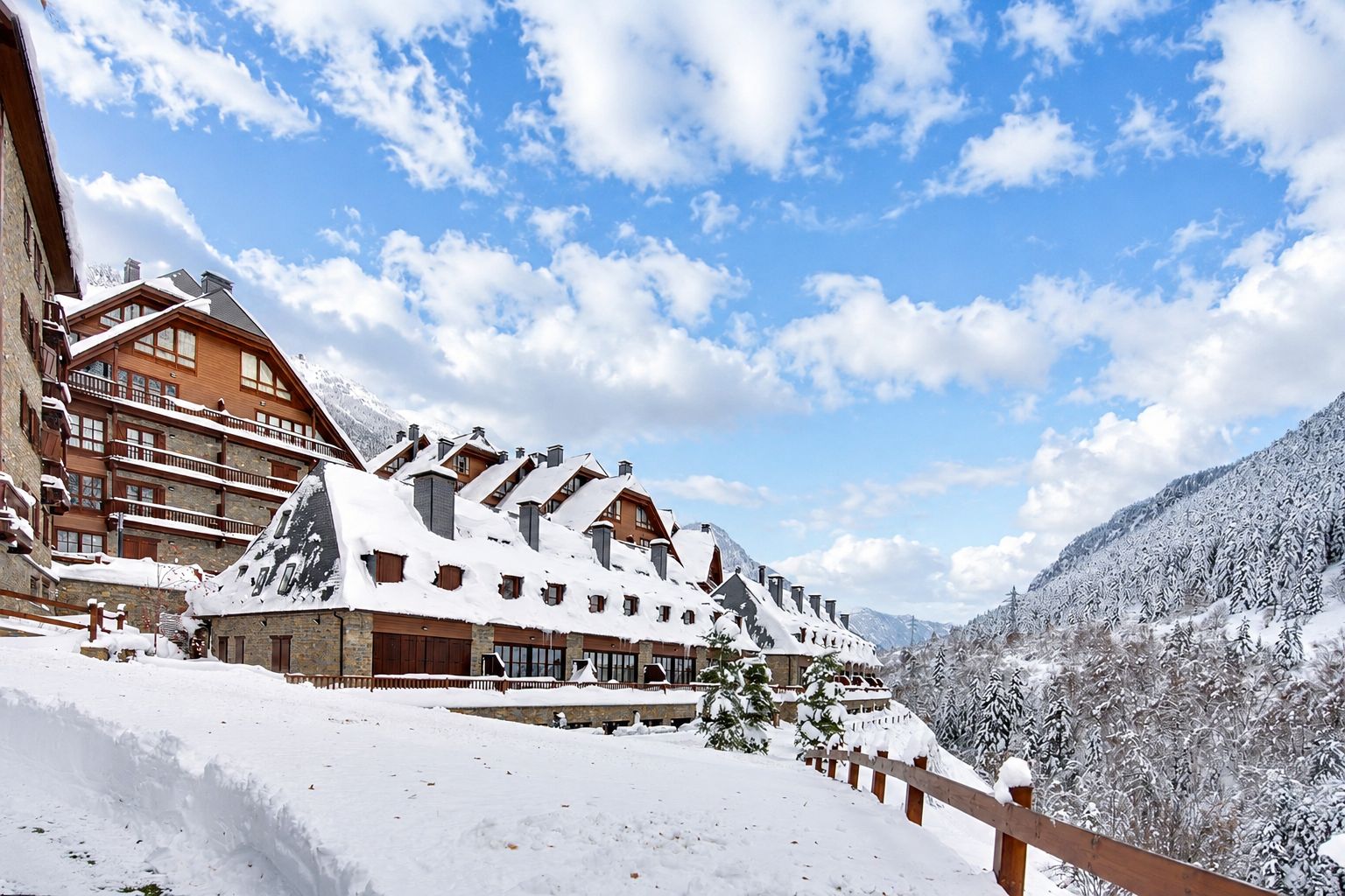 A snow-covered mountain lodge with multiple levels, wooden balconies, and a ski slope in the background.