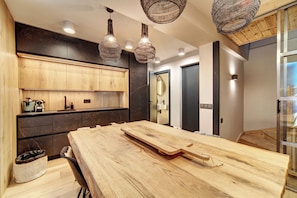 A modern kitchen with wooden cabinets, a large wooden table, and hanging woven light fixtures. - Casa Val de Ruda Luxe 78 by FeelFree Rentals (Naut Aran)