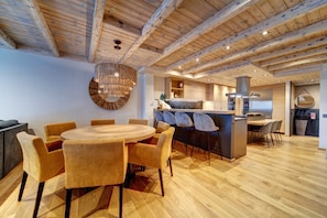 A modern kitchen with wooden beams, a round dining table with chairs, and a bar area. - Casa Val de Ruda Luxe 78 by FeelFree Rentals (Naut Aran)