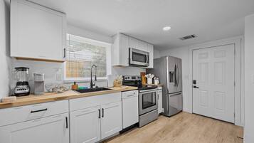A modern kitchen with white cabinets, stainless steel appliances, a microwave, oven, and refrigerator.