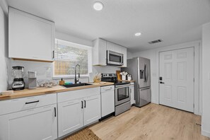 A modern kitchen with white cabinets, stainless steel appliances, a microwave, oven, and refrigerator. - Tarrytown Loft | Private Patio + Workspace (Austin)