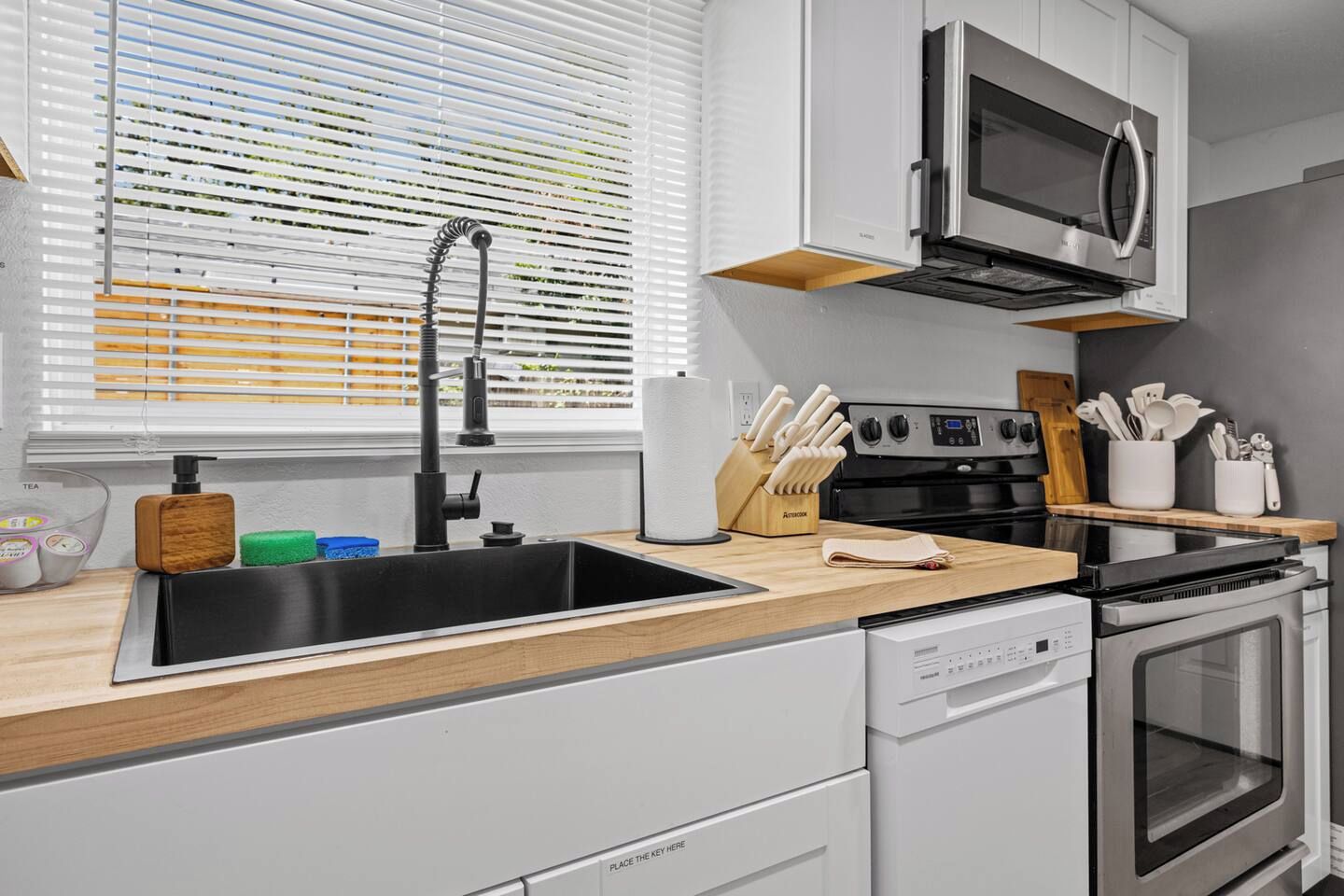 A modern kitchen with a stainless steel sink, a built-in oven, and a microwave.