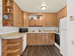 A kitchen with wooden cabinets, a microwave, a sink, and a refrigerator. - Summit Nook | 2 bdrm Brian Head Condo (Brian Head)