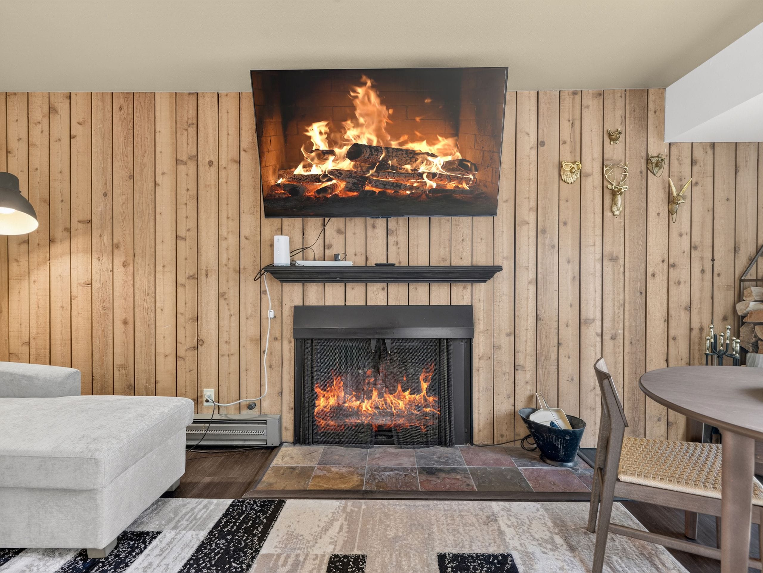 A living room with a fireplace, a sofa, a dining table, and a rug.