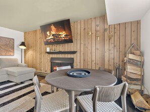A modern living room with a fireplace, a round dining table, and a sofa. - Summit Nook | 2 bdrm Brian Head Condo (Brian Head)