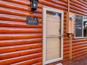 A log cabin with a beige double door, a mailbox, and a window with a wooden frame. - Old Tymer Retreat nestled in the mountains (Duck Creek Village)