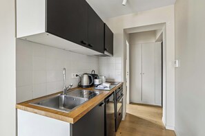 Una cocina moderna con encimera de madera, pileta de acero inoxidable y alacenas negras.