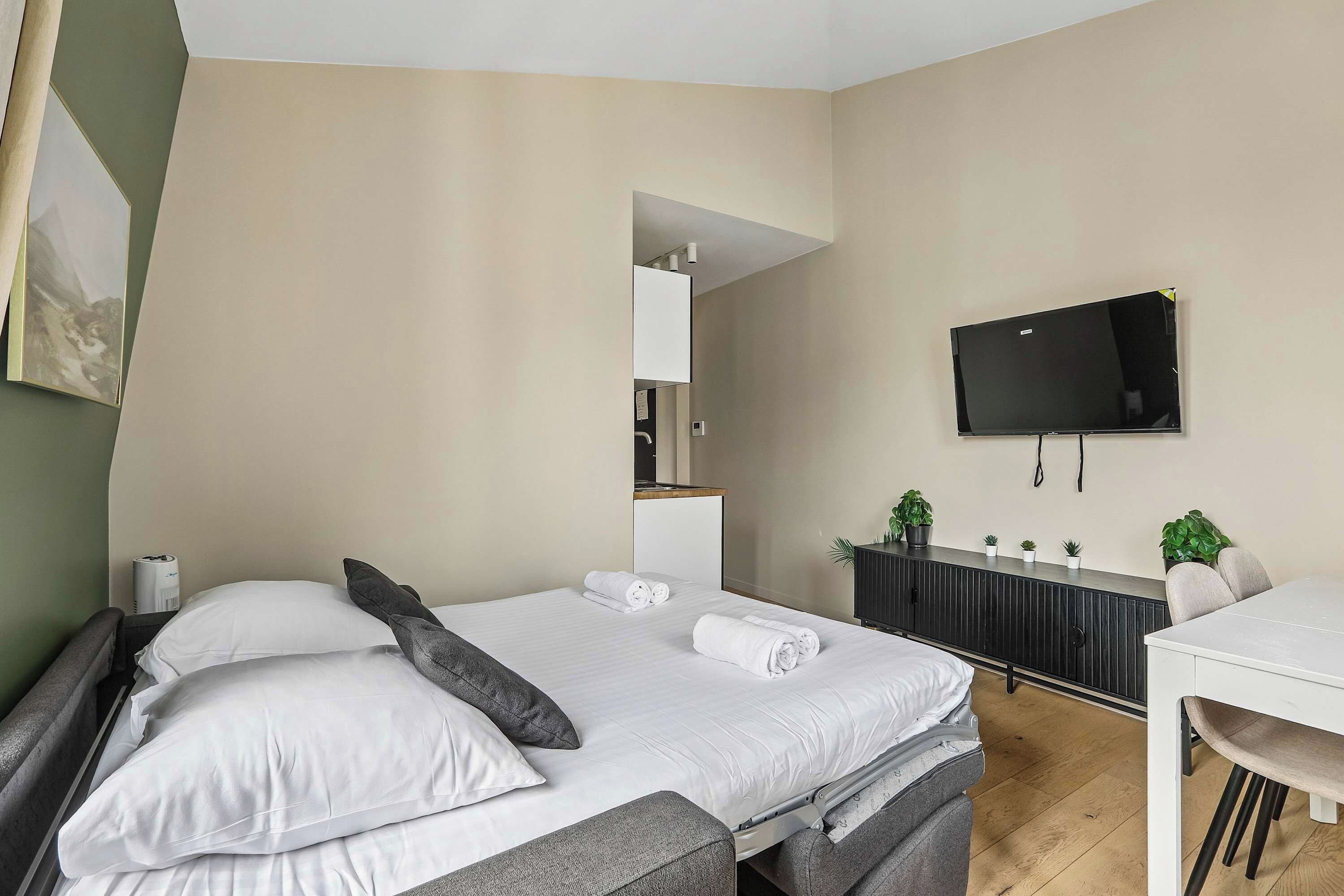 Une chambre d’hôtel avec deux lits, un bureau, une télévision et une plante en pot.