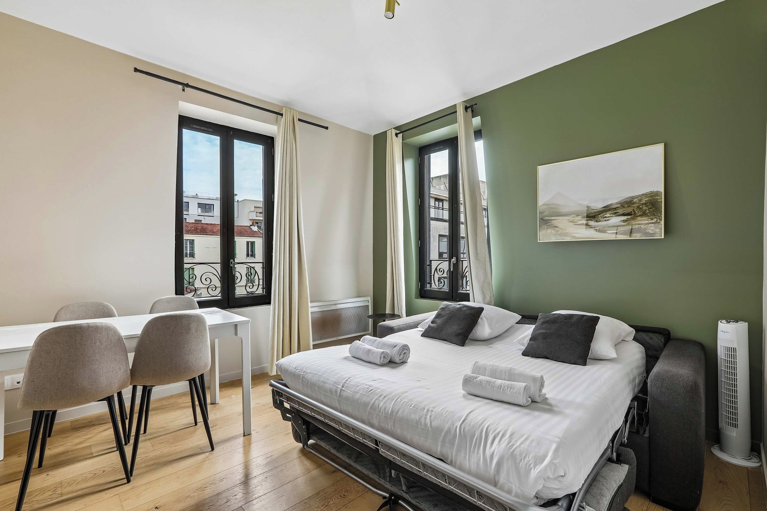 Une chambre d’hôtel avec un lit, un bureau, des chaises et une fenêtre avec des rideaux.