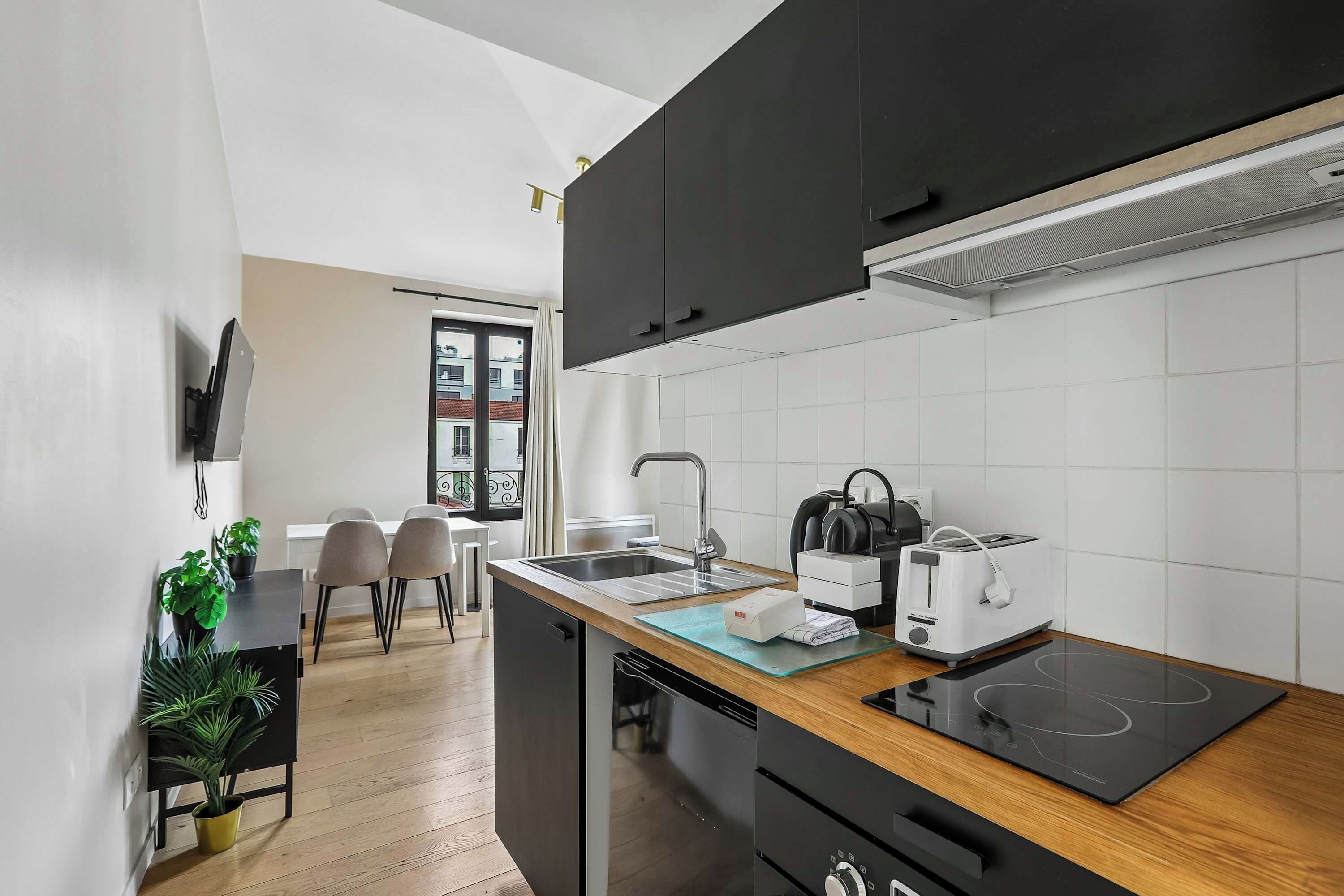 Eine moderne Küche mit schwarzen Schränken, einem Einbauofen, einem Toaster und einer Spüle.