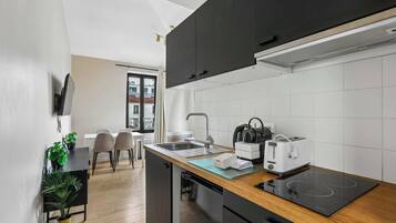 Eine moderne Küche mit schwarzen Schränken, einem Einbauofen, einem Toaster und einer Spüle.