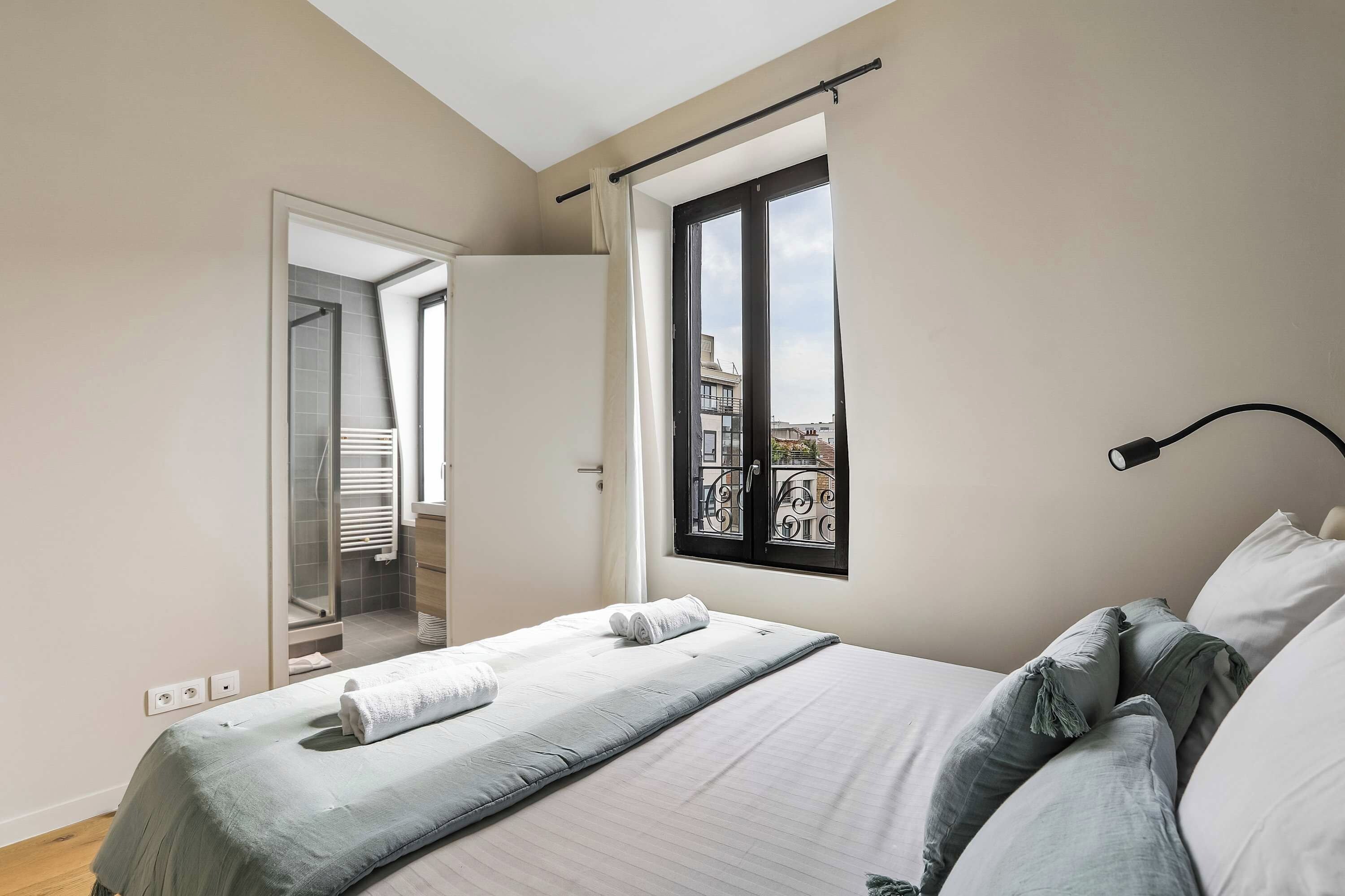Une chambre à coucher avec un lit, une fenêtre donnant sur un paysage agréable, une porte et un luminaire.