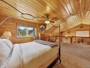 A bedroom with a bed, a ceiling fan, a window, and a view of the outdoors. - Uncle Jim's Cabin | 2 Cabins | Family + Dog Friendly (Panguitch)