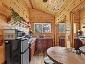 A wooden cabin interior with a kitchen area featuring a refrigerator, microwave, and coffee maker. - Uncle Jim's Cabin | 2 Cabins | Family + Dog Friendly (Panguitch)