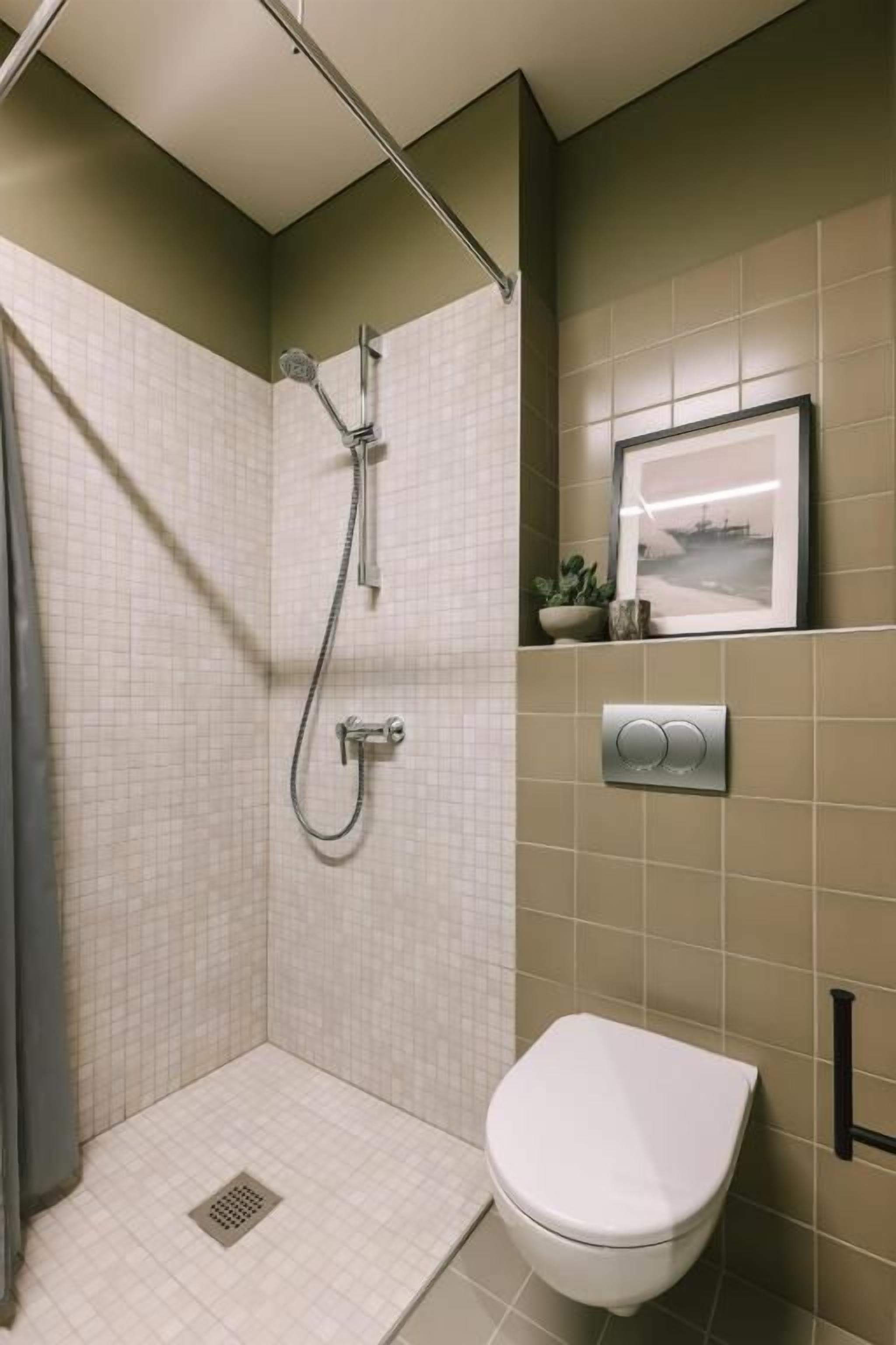 Une salle de bain avec une douche, des toilettes et un tableau encadré au mur.
