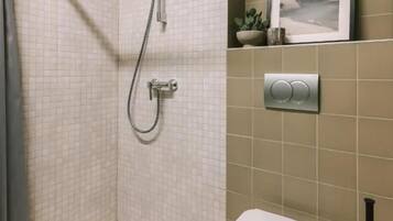 Une salle de bain avec une douche, des toilettes et un tableau encadré au mur.