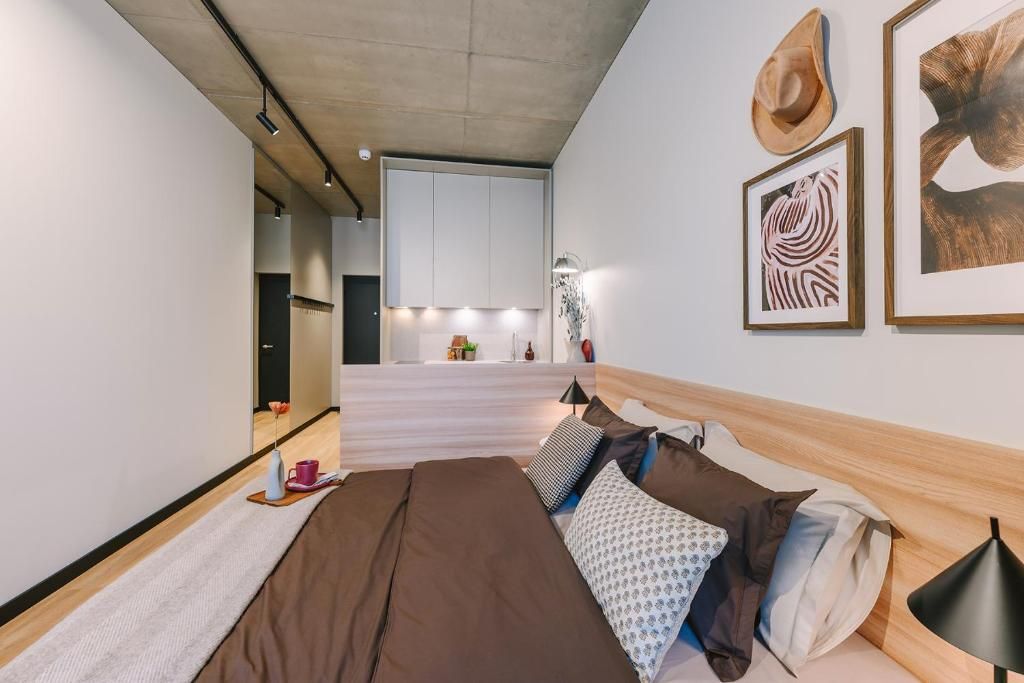 Una camera da letto moderna con un letto, cuscini, un comodino e una lampada.