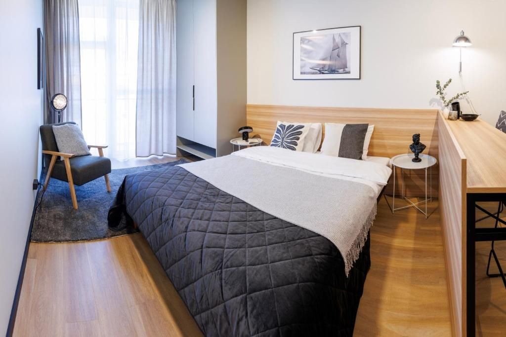 Una habitación de hotel moderna con una cama grande, un escritorio, una silla y una mesita de noche.