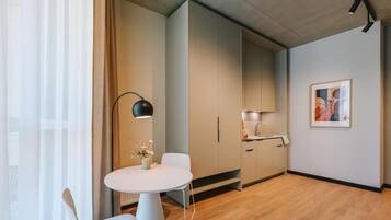 A modern kitchen with wooden cabinets, a white countertop, and a small dining area with a round table and chairs.