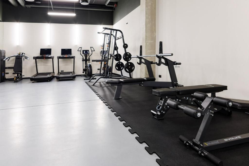 Ein Fitnessstudio mit Laufbändern, Kraftgeräten und einer Bank.