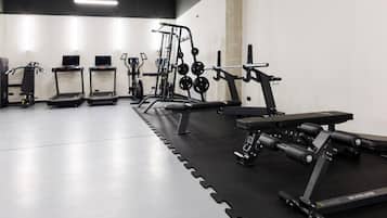 Ein Fitnessstudio mit Laufbändern, Kraftgeräten und einer Bank.