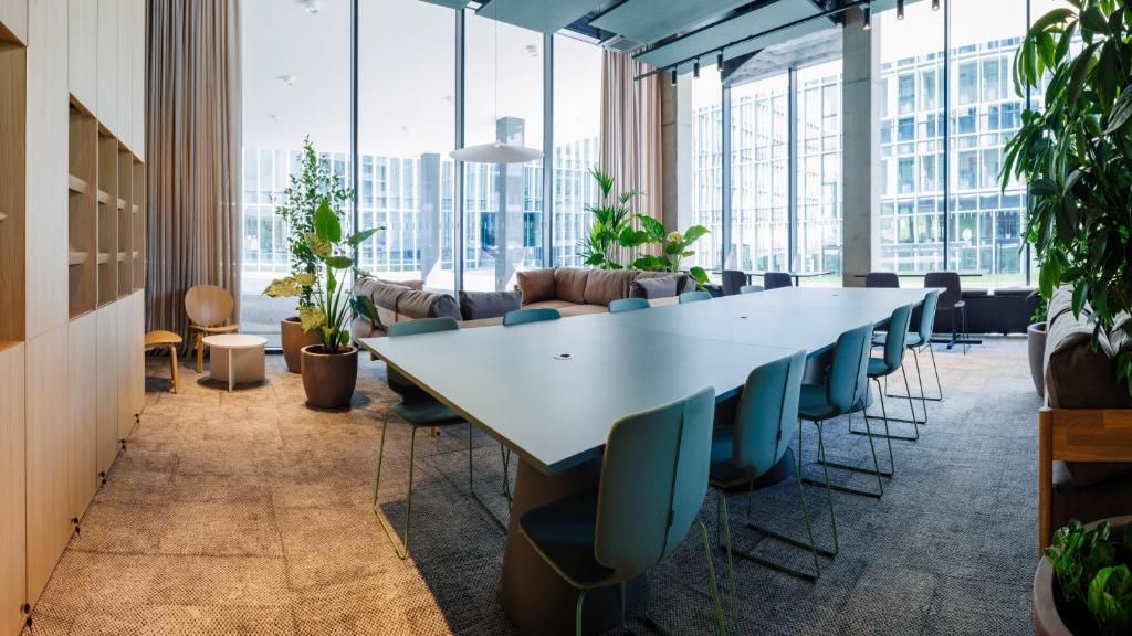 A modern conference room with a long table, chairs, and potted plants.