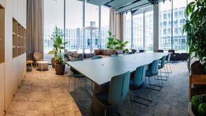 A modern conference room with a long table, chairs, and potted plants.
