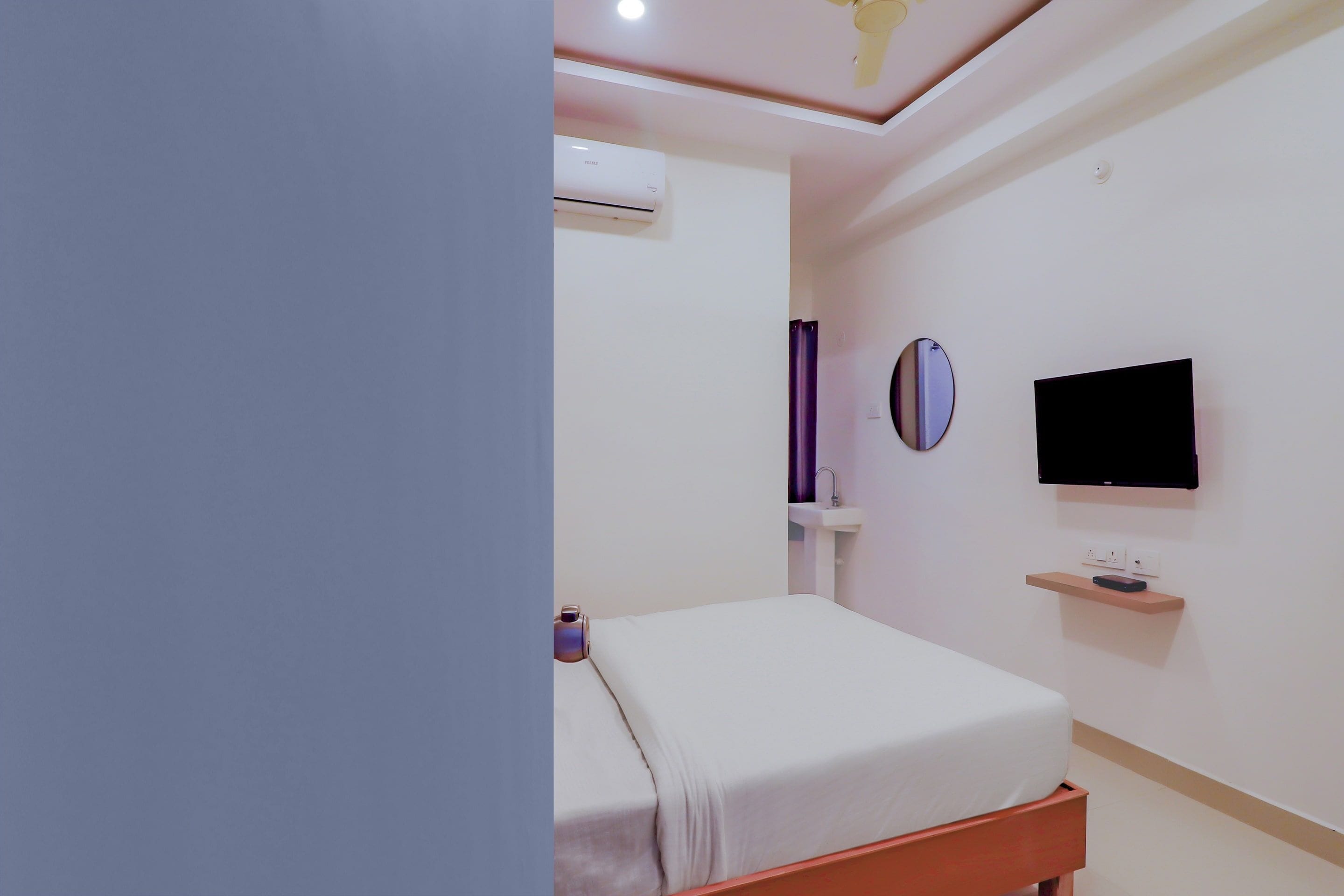 A modern bedroom with a bed, a television mounted on the wall, and an air conditioning unit.